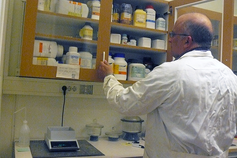 Art Ragauskas removes supplies from a cabinet in a lab.
