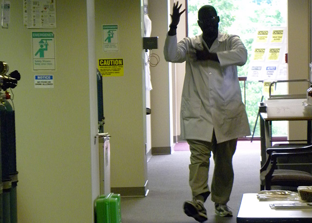 Researcher pulls on gloves in a hallway.